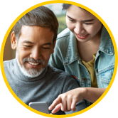 Daughter teaching father how to access Sun Life Preferred Pharmacy Network on mobile phone. 